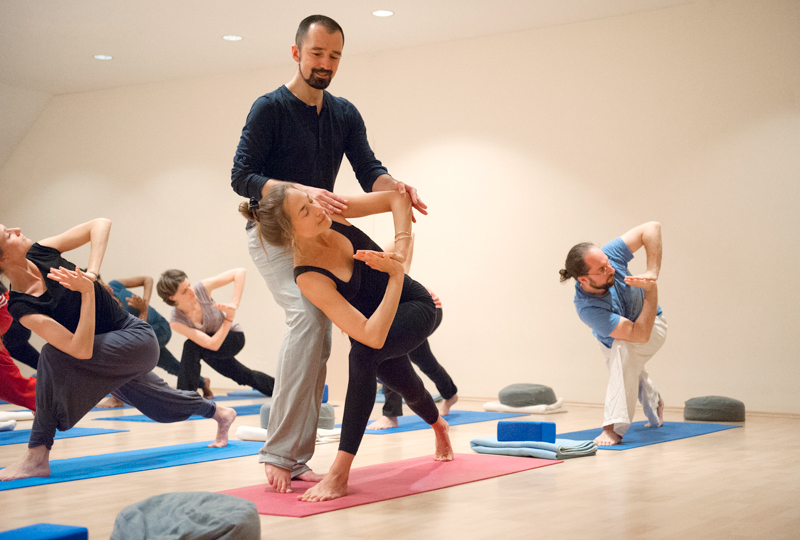 Yogalehrer Alexander Kröker mit Yogaschülerin unterstützt bei Alignment Asana Yogalehrer Berlin Weiterbildung Fortbildung