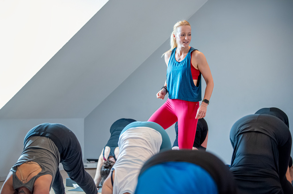 Element Yogalehrerin Nadin beim Yogaunterrichten zwischen Schüler:innen gehend