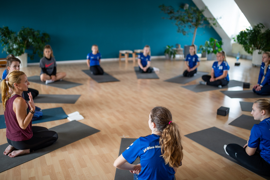 Teen Yoga und Kinder Yogalehrerinnen Ausbildung mit Kindern und Jugendlichen, die im Kreis auf Yogamatten sitzen